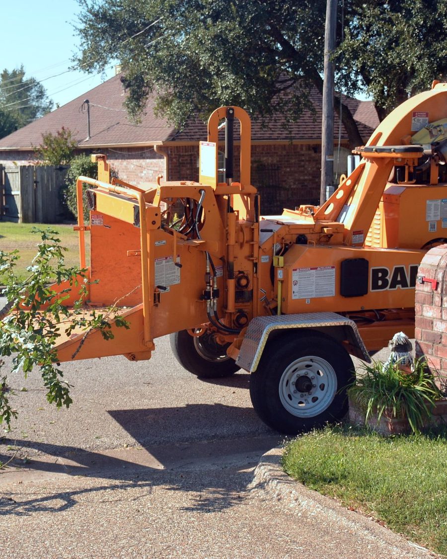 A wood chipper parked at the kerb with cut brush beside it